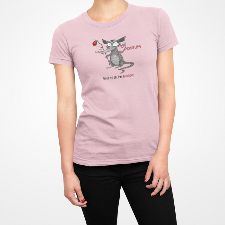 Person wearing a pink t-shirt with a cartoon possum design on a white background with the wording Pussum First of all, I'm a Delight