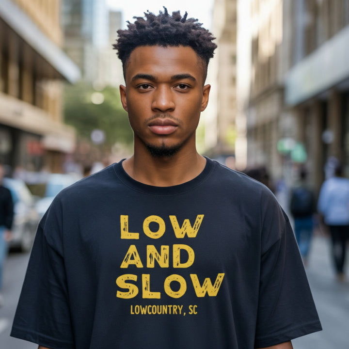 Man wearing a black t-shirt with 'Low and Slow Lowcountry, SC' text on a city street.
